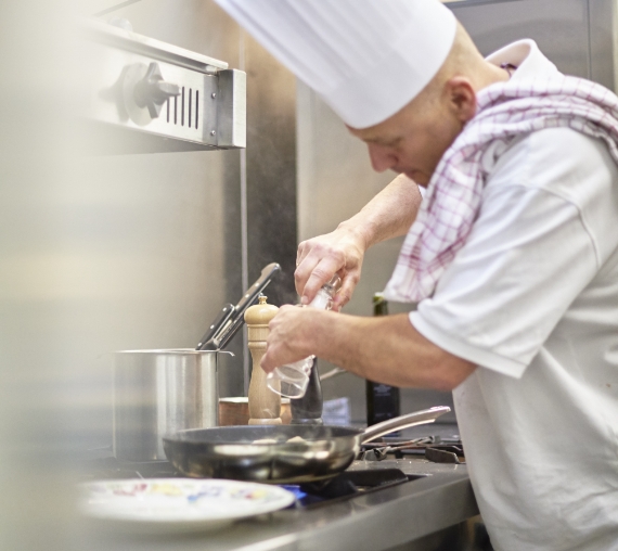 Chef Patrick die aan het koken is in de keuken van Restaurant De Colvenier Antwerpen